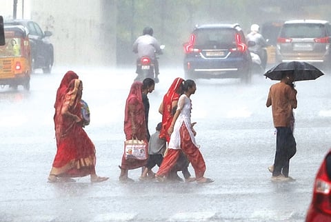 A group of women crossing the road during heavy rainfall.