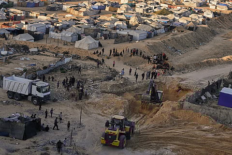 Palestinians watch machinery and some workers from Egypt searching for the bodies of hostages at Hamad City, in Khan Younis, southern Gaza Strip, Monday, Oct. 27, 2025. 