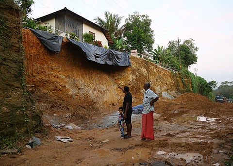 Residents point towards the sight of mudslip at Kollikkadu, Kothamangalam. A house hungs precariously over the  edge of the slope where the bypass works are progressing.