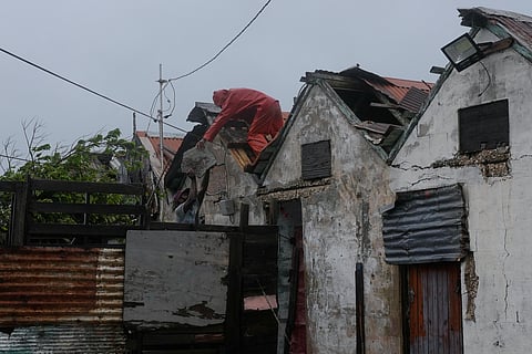 Men remove a loose section of roof in Kingston, Jamaica, as Hurricane Melissa approaches, Tuesday, Oct. 28, 2025.