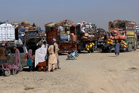 Afghan refugees gather beside trucks loaded with their belongings as they wait their turn to leave for their homeland through a border crossing point which partially opens following the Oct. 19 ceasefire, on the outskirts of Chaman, a border town on the Pakistan-Afghan border, Wednesday, Oct. 29, 2025.