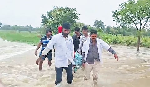 A pregnant woman being carried by 108 ambulance staff across a stream in
Devarakonda.