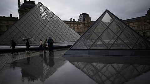 People tour the courtyard of the Louvre museum in the rain on Monday, Oct. 27, 2025, in Paris.