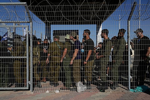 Israeli soldiers gather at the gate to the Sde Teiman military base, as people protest in support of soldiers being questioned for detainee abuse, July 29, 2024.