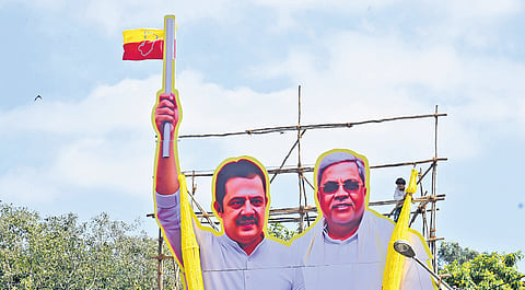 A worker fixes a cutout of CM Siddaramaiah and minister BZ Zameer Ahmed Khan, ahead of Kannada Rajyotsava, in Bengaluru on Friday.