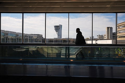 A traveler moves in view of a control tower at Philadelphia International Airport in Philadelphia, Wednesday, Nov. 5, 2025.
