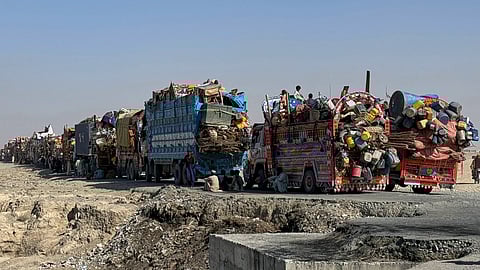 Afghan refugees sit beside trucks loaded with their belongings as they wait their turn to leave for their homeland through a border crossing point which partially opened following the Oct. 19 ceasefire, on the outskirts of Chaman, a border town on the Pakistan-Afghan border, Wednesday, Oct. 29, 2025.