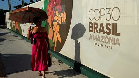 A woman walks past a sign for the COP30 U.N. Climate Summit, in Belem, Para state, Brazil, Tuesday, November 4, 2025.