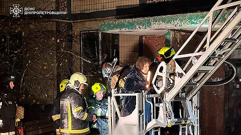 In this photo provided by the Ukrainian Emergency Service, firefighters evacuate a resident following a Russian rocket attack that hit a multi-storey apartment building in Dnipro, Ukraine, Saturday, Nov. 8, 2025.