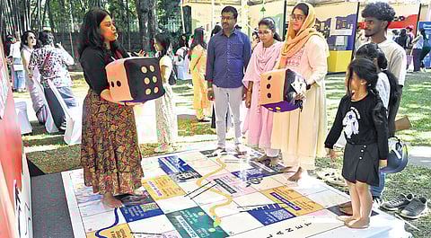 Visitors try out Inner Planeta’s creative twist on the classic snakes and ladders game at Manotsava 2025, to highlight mental health journeys and the ups and downs of emotional well-being in children, in Bengaluru on Sunday 