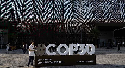 A person poses for a photo with a sign for the COP30 U.N. Climate Summit.