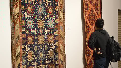 Visitor looks at a carpet on display at Gallery Sumukha