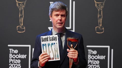 Hungarian-British author David Szalay poses for photographers with the trophy after winning the Booker Prize 2025 for his book 'Flesh' during a ceremony at Old Billingsgate in London, Monday, Nov. 10, 2025.