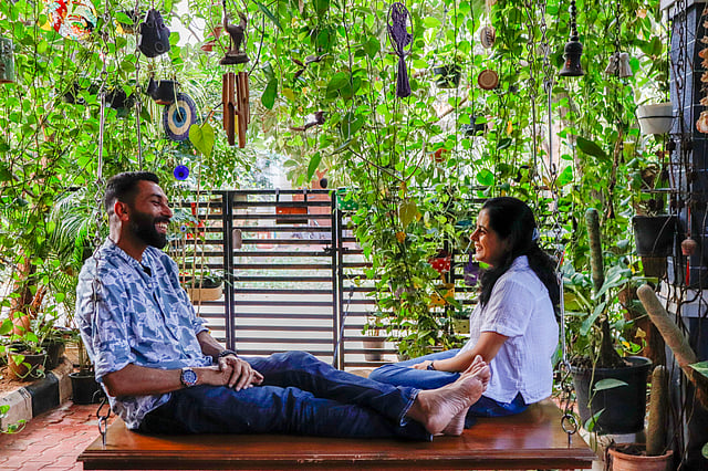 Homeowners Sumesh and Meethu Nayak sit on a wooden swing adorning their green verandah