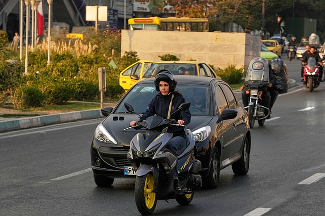 A woman drives her motorbike in downtown Tehran, Iran, Saturday, Nov. 8, 2025