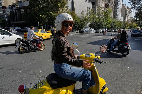 Iranian woman Merat Behnam speaks on her motorbike in downtown Tehran, Iran, Saturday, Nov. 1, 2025.