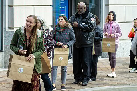 Federal workers stand in line to pickup meals from the World Central Kitchen, Wednesday, Nov. 12, 2025, in Washington.