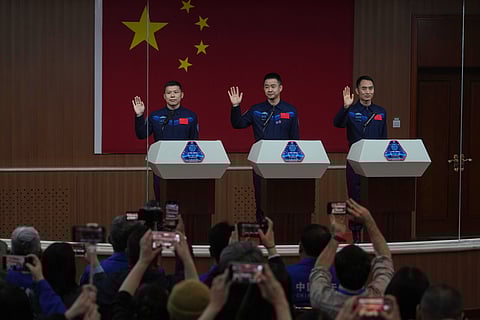 FILE - Journalists film Chinese astronauts for the upcoming Shenzhou 20 mission, from left, Wang Jie, captain Chen Dong and Chen Zhongrui wave at the Jiuquan Satellite Launch Center in northwest China, Wednesday, April 23, 2025. 