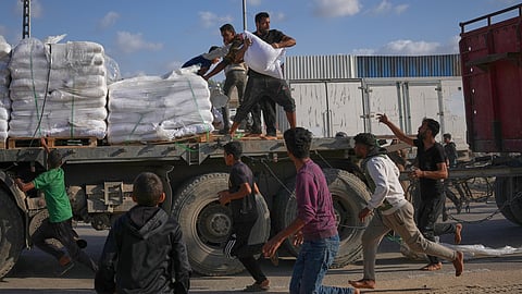Palestinians grab sacks of flour from a moving truck carrying World Food Programme (WFP) aid as it drives through Deir al-Balah in central Gaza, Saturday, Nov. 15, 2025