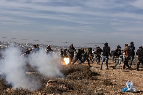 Hilltop Youth run for cover as they clash with Israeli security forces evacuating and demolishing an illegal outpost built near the Jewish settlement of Metzad east of the Palestinian city of Sa’ir in the occupied West Bank, on November 17, 2025.