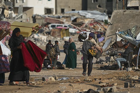 A Palestinian man carries bags of firewood after collecting them from the rubbish in Khan Younis, southern Gaza Strip, on Saturday, Nov. 15, 2025