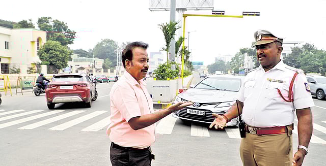 G Manuneethi discusses traffic flow changes with a police personnel in Coimbatore  