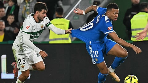 Elche's Spanish defender Victor Chust grasps the jersey of Real Madrid's Kylian Mbappe during the Spanish league football match between Elche CF and Real Madrid CF at Martinez Valero Stadium in Elche on November 23, 2025. 