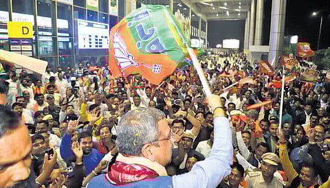 Union Minister Pradhan waving a BJP flag at party workers outside VSS Airport | Express