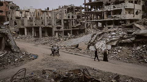 Palestinians walk among the ruins of destroyed buildings in Gaza City Monday, Nov. 24, 2025