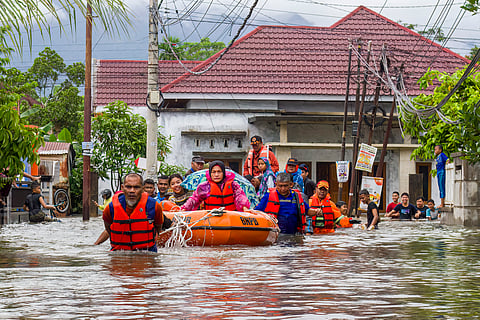 A rescue team evacuates women and children in a rubber boat as floodwaters hit a residential area in Padang, West Sumatra on November 25, 2025.