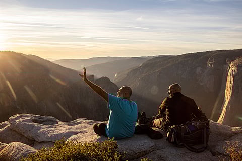isitors watch a sunset on rock ledge near Taft Point in Yosemite National Park.