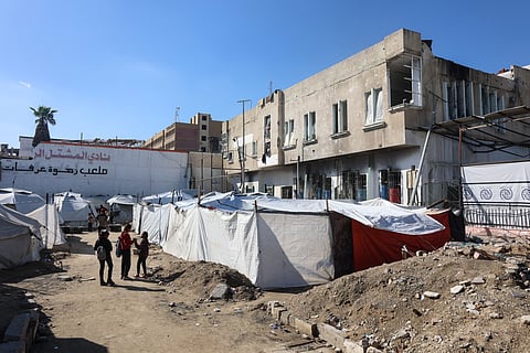 Palestinian children stand outside the partially damaged Al-Mushtal Sports Club in Gaza City on November 26, 2025.