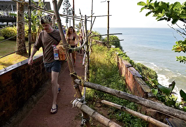 Tourists walking down a path by fragile cliff edge