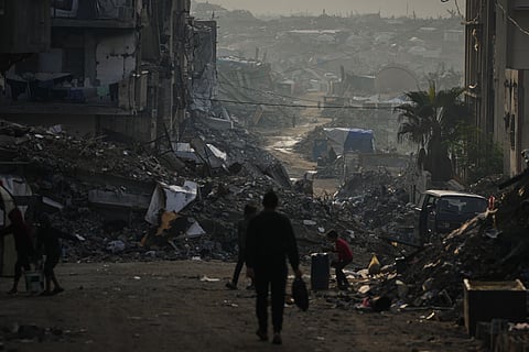 Palestinians walk through the destruction left by the Israeli air and ground offensive in Gaza City, Saturday.