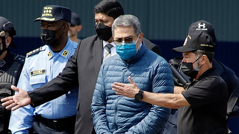 Former Honduran President Juan Orlando Hernandez, second from right, is taken in handcuffs to a waiting aircraft as he is extradited to the United States at an Air Force base in Tegucigalpa, Honduras, April 21, 2022.