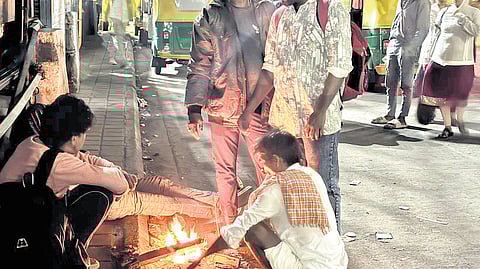 Waiting to catch the first bus, a group of people huddle over a fire at Majestic Bus Terminal early on Sunday morning