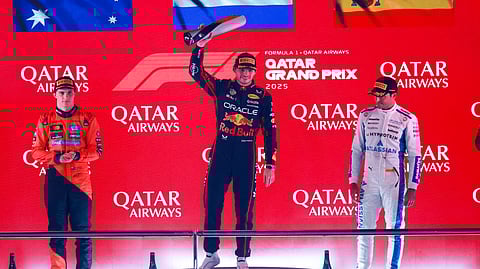 Race winner Red Bull Racing's Max Verstappen (C) celebrates with the trophy next to second placed McLaren's Oscar Piastri (L) and third placed Williams' Carlos Sainz at the end of the Formula One Qatar Grand Prix on November 30, 2025.