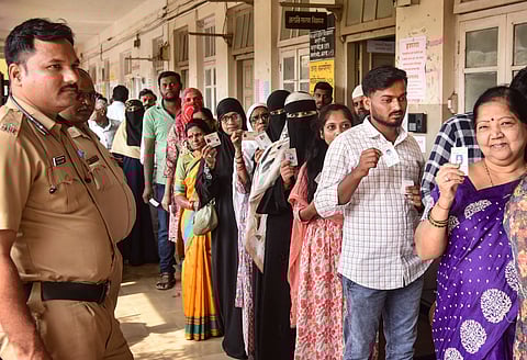 People wait in a queue to cast their votes at a polling booth during the Maharashtra local body elections, in Karad, Tuesday, Dec. 2, 2025.