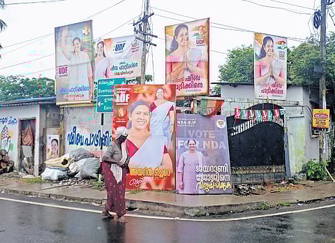 A woman walks past a bunch of flex boards of candidates fielded by various political fronts at Valiyathura in Thiruvananthapuram 