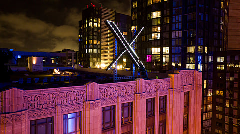 Workers install lighting on an "X" sign atop the company headquarters in downtown San Francisco, July 28, 2023. 