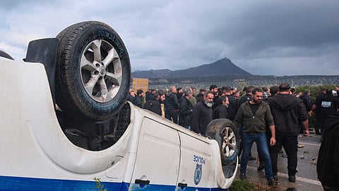 Farmers gather next to an overturned police vehicle during clashes with officers blocking their march to Chania's airport on Crete, Greece, Monday, Dec. 8, 2025, amid protests over delayed EU farm subsidies.