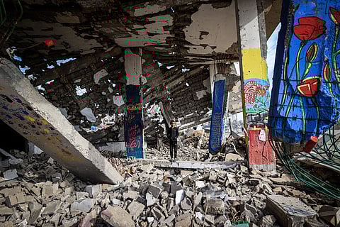 A boy stands amid murals painted on a destroyed building in the Maghazi refugee camp outside Deir al-Balah on December 8, 2025.
