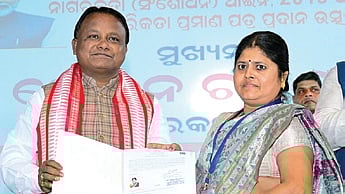 CM Mohan Charan Majhi hands over the citizenship papers to a woman refugee