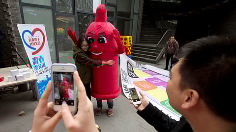 A participant hugs a condom mascot during an event to promote awareness of HIV testing ahead of the Dec 1 World AIDS Day, in Beijing, China, Thursday, Nov. 27, 2014. 
