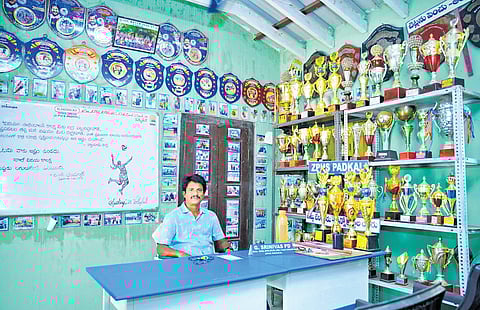 Physical director Gaddam Srinivas poses with several trophies and plaques won by the school.