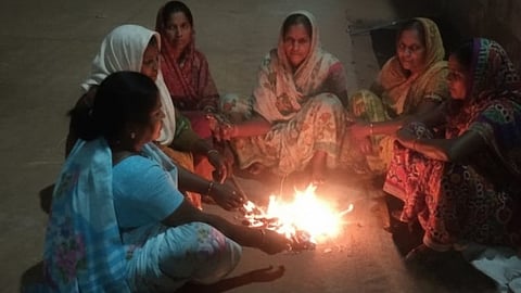 Women gather around a bonfire to keep themselves warm in Sangareddy on Friday