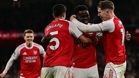 Arsenal's Bukayo Saka (C) celebrates with teammates after his corner kick is diverted into his own net by Wolverhampton Wanderers' goalkeeper Sam Johnston during the EPL football match between Arsenal and Wolverhampton on December 13, 2025. 