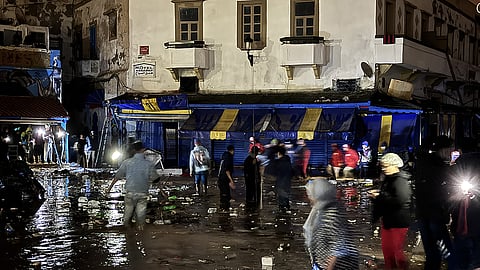 People wade through a square after a flash flood in Safi on December 14, 2025.