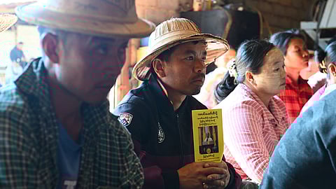 This photo taken on December 9, 2025, shows a man holding an election campaign pamphlet at a People's Party event ahead of Myanmar's general election in Nawnghkio in Myanmar’s northern Shan State.