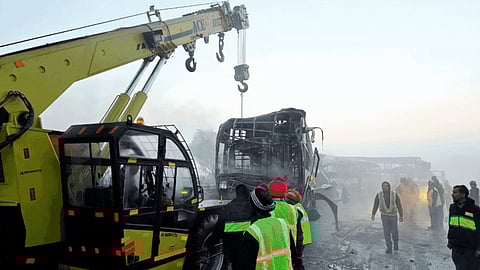 Cranes clear the charred remains of buses after a fog-hit pile-up involving several buses and cars triggered fires on the Yamuna Expressway, in Mathura, Tuesday, Dec. 16, 2025.